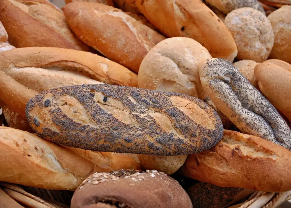 Mand met verschillende soorten vers brood, waaronder maanzaadbrood en bolletjes